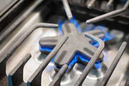 Detailed View of a Gas Range Burner Head with a Blue Flame
