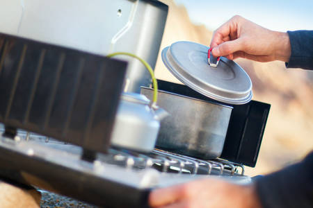 Detailed View of a Man Cooking Meal on a Camping Stove