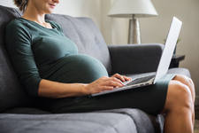 Pregnant Woman Sitting on a Sofa and Working on a Laptop