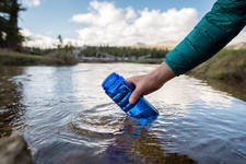 Woman Filling a Bottle with Pure Water from a Mountain Creek Woman Filling a Bottle with Pure Water from a Mountain Creek